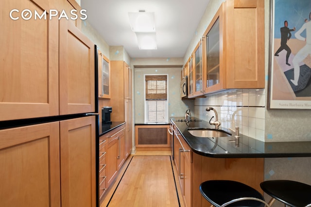 1065 Park Ave Unit 11A, New York City, NY 10128 - kitchen featuring a sink, light wood-style floors, glass insert cabinets, tasteful backsplash, and a breakfast bar area