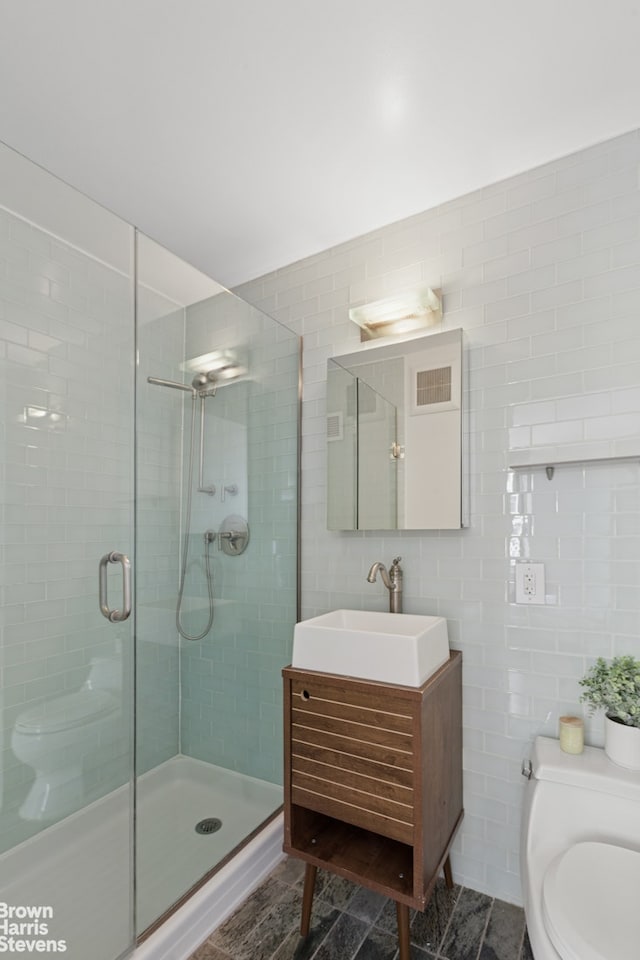 bathroom with tile walls, toilet, a shower stall, and vanity