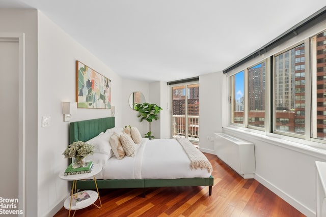 bedroom with wood finished floors, radiator heating unit, and baseboards