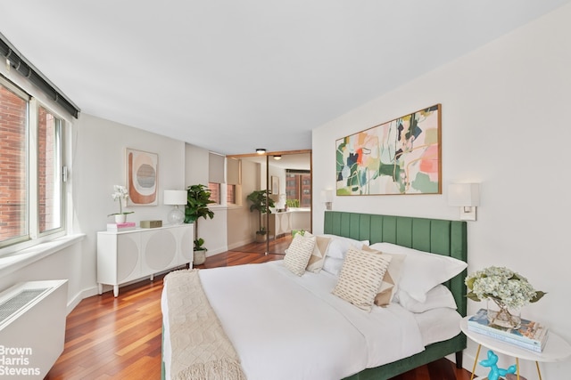 bedroom featuring wood finished floors, radiator heating unit, and baseboards