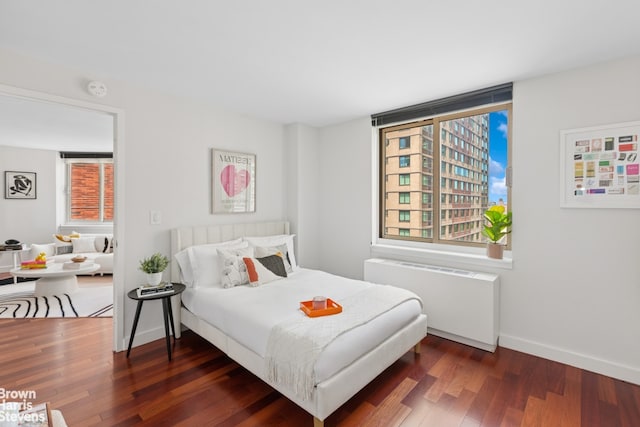bedroom featuring radiator, wood finished floors, and baseboards