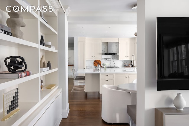 40 E 66th St Unit 12B, New York City, NY 10065 - kitchen with wall chimney range hood, white cabinets, backsplash, dark wood-type flooring, and light countertops