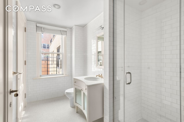 40 E 66th St Unit 12B, New York City, NY 10065 - bathroom with vanity, tile walls, toilet, a stall shower, and tile patterned flooring