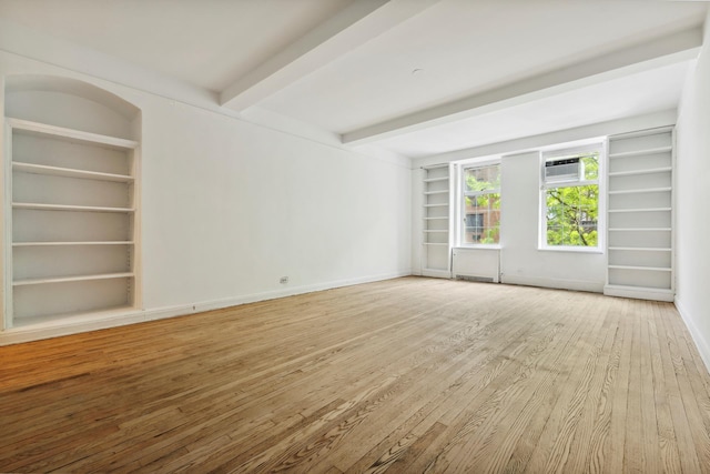unfurnished room with built in features, wood finished floors, beam ceiling, baseboards, and a wall mounted air conditioner