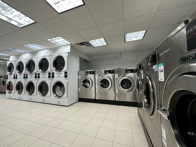 communal laundry room with washing machine and clothes dryer and light tile patterned flooring