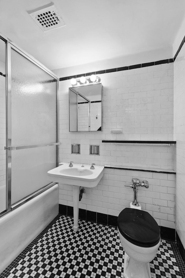 410 W 24th St Unit 4L, New York City, NY 10011 - bathroom with combined bath / shower with glass door, tile patterned floors, toilet, and tile walls