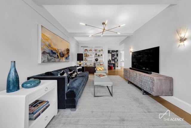living room featuring a chandelier, built in shelves, light wood-style flooring, and baseboards