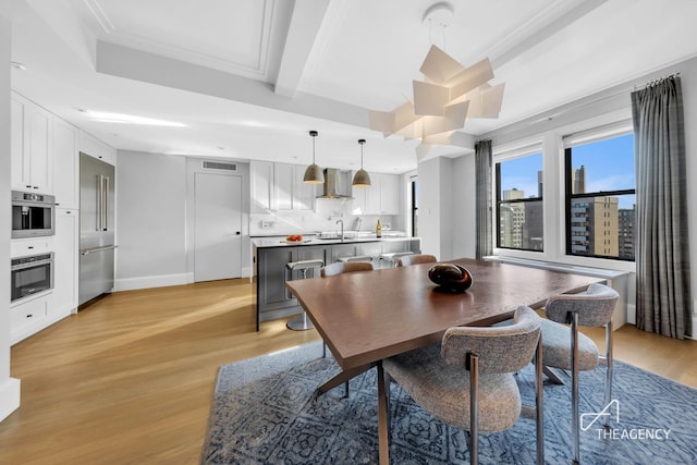 dining area featuring light wood-style flooring, baseboards, beam ceiling, and crown molding