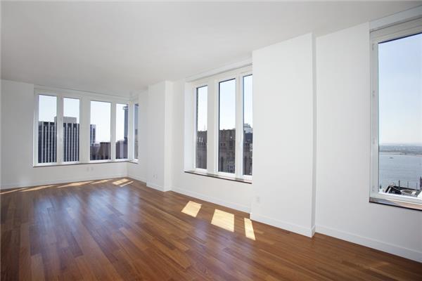 spare room with healthy amount of natural light, baseboards, and wood finished floors