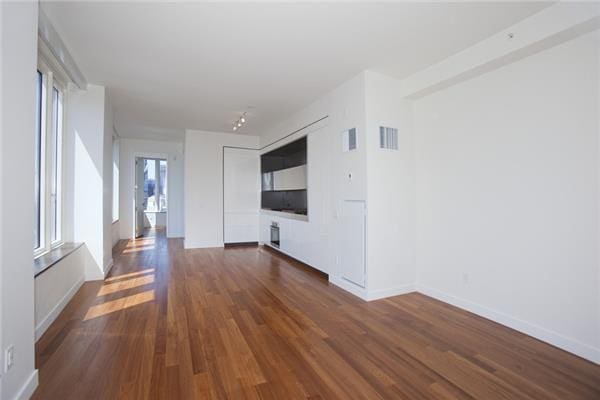 15 William St Unit 42-A, New York City, NY 10005 - unfurnished living room featuring dark wood-type flooring and baseboards
