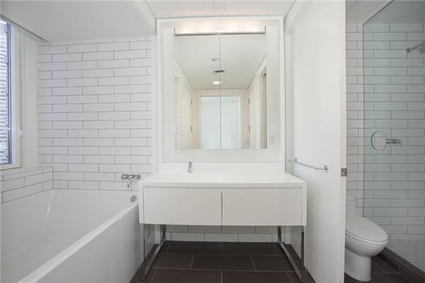 full bath with toilet, tiled shower, a tub to relax in, vanity, and tile patterned flooring