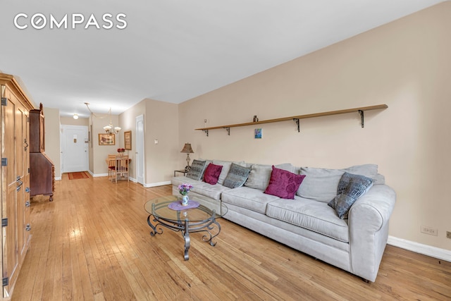 living area with light wood-style flooring, baseboards, and a chandelier