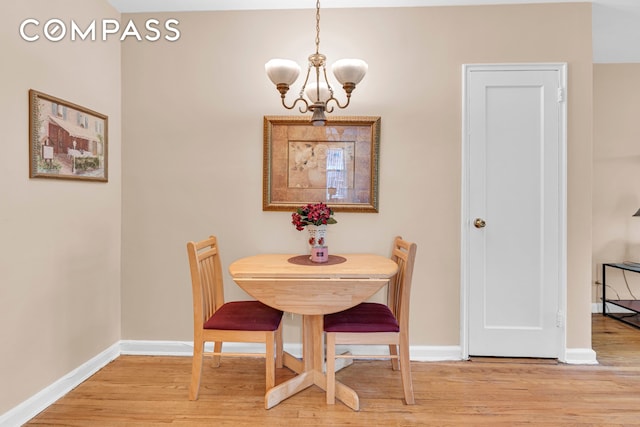 dining area with a chandelier, light wood-type flooring, and baseboards
