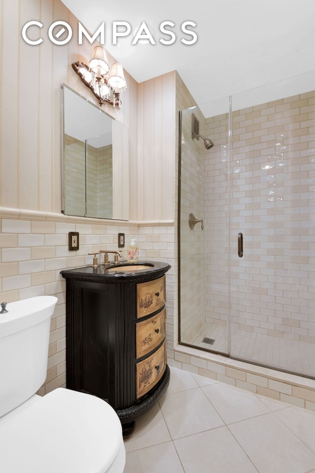 full bath featuring a shower stall, tile walls, toilet, vanity, and tile patterned floors