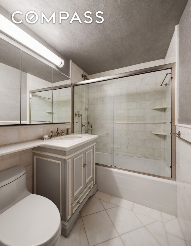bathroom with toilet, bath / shower combo with glass door, vanity, a textured ceiling, and tile patterned flooring