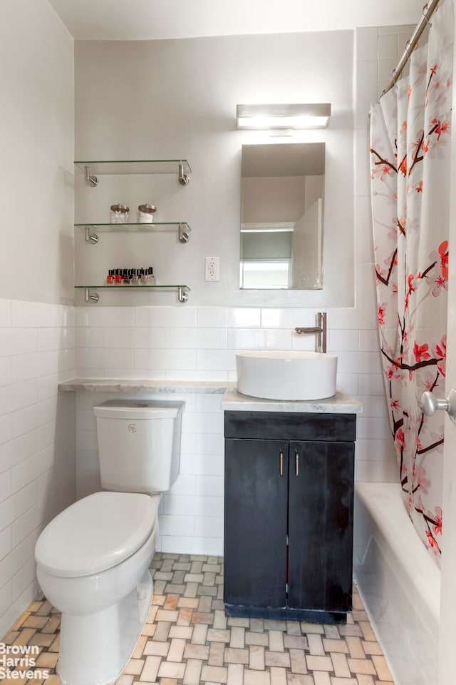 bathroom with tile walls, toilet, wainscoting, vanity, and shower / bath combo