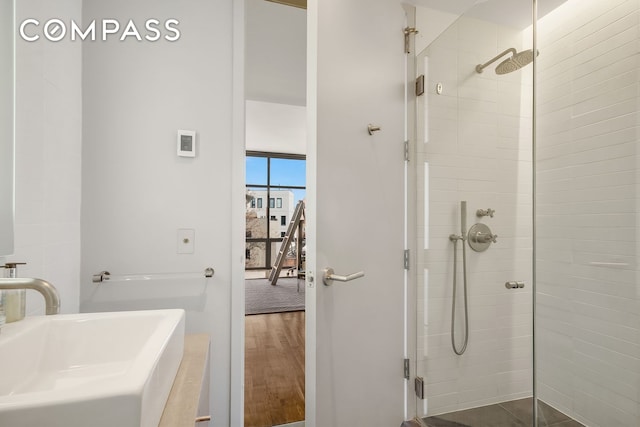 full bathroom featuring a sink, a stall shower, and wood finished floors