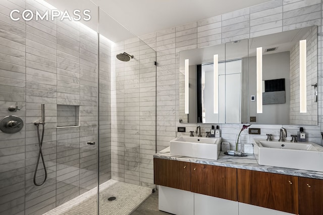 full bathroom with a shower stall, tile walls, and double vanity