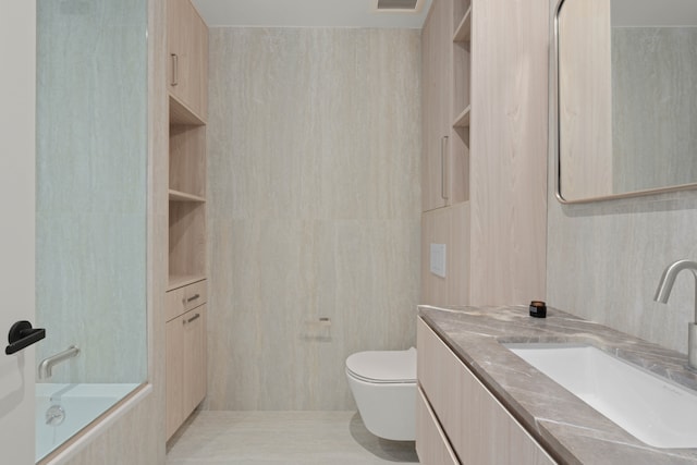 bathroom featuring toilet, vanity, and tile walls
