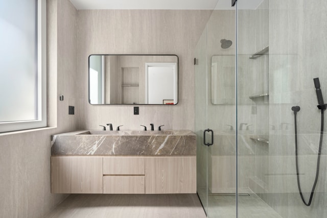 bathroom with a stall shower and double vanity