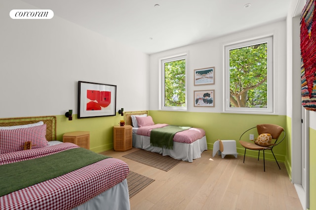 bedroom with multiple windows, baseboards, and light wood-type flooring