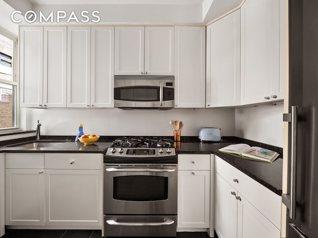 25 5th Ave Unit 8F, New York City, NY 10003 - kitchen featuring stainless steel appliances, a sink, white cabinets, and dark stone countertops
