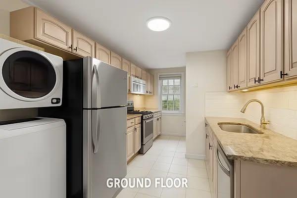 124 President St, New York City, NY 11231 - kitchen featuring stainless steel appliances, a sink, estacked washer and dryer, baseboards, and light tile patterned flooring