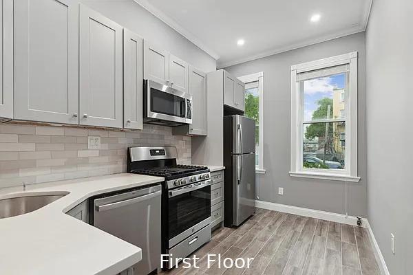 124 President St, New York City, NY 11231 - kitchen with appliances with stainless steel finishes, crown molding, tasteful backsplash, light countertops, and light wood-type flooring