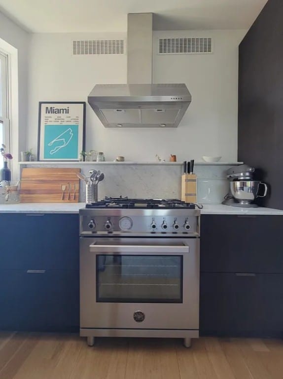 kitchen featuring high end range, wall chimney exhaust hood, light countertops, modern cabinets, and blue cabinetry