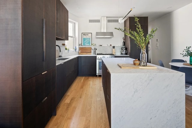 kitchen with white gas stove, a sink, modern cabinets, and light wood finished floors