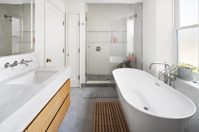 full bathroom with a shower stall, a freestanding tub, vanity, and plenty of natural light