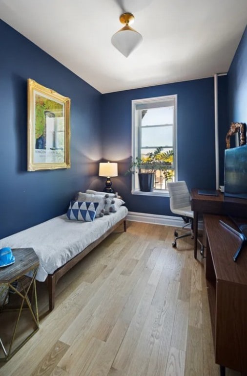 bedroom featuring wood finished floors, an office area, and baseboards