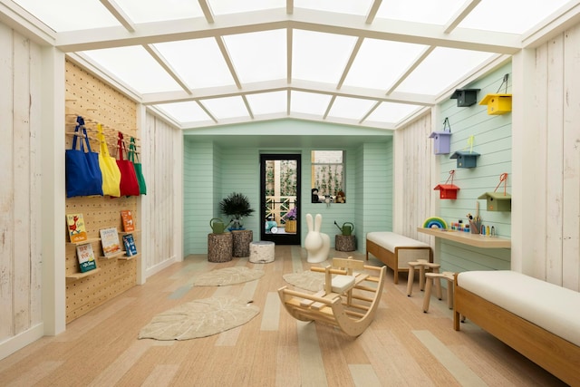 living room featuring lofted ceiling, wooden walls, and baseboards