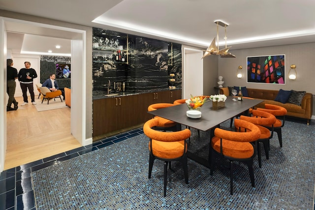 dining area featuring a community bar, a tray ceiling, and tile patterned flooring