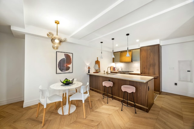 kitchen with a sink, a breakfast bar area, light countertops, baseboards, and a peninsula