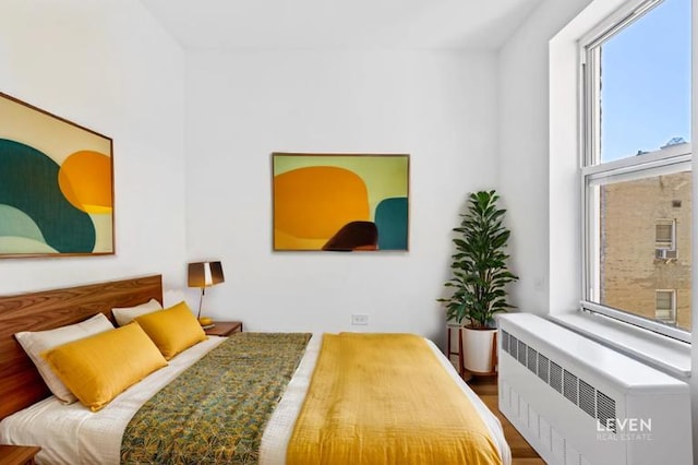 bedroom featuring radiator heating unit and wood finished floors