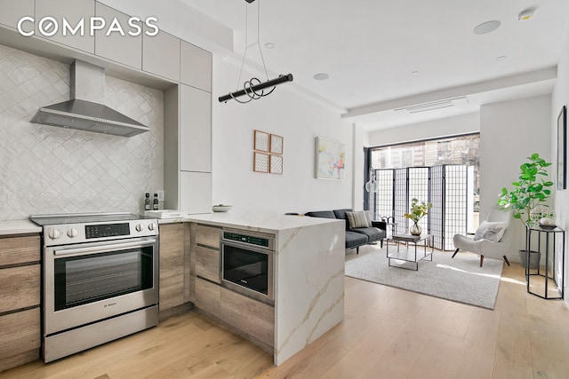 kitchen with stainless steel appliances, wall chimney range hood, modern cabinets, a peninsula, and open floor plan