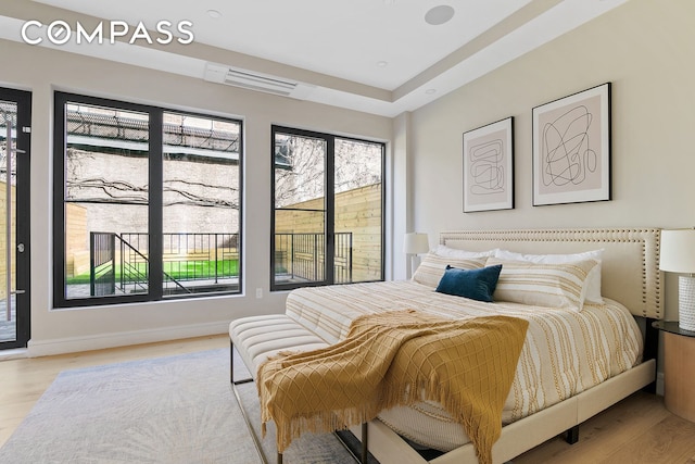 bedroom with multiple windows, light wood-type flooring, and baseboards