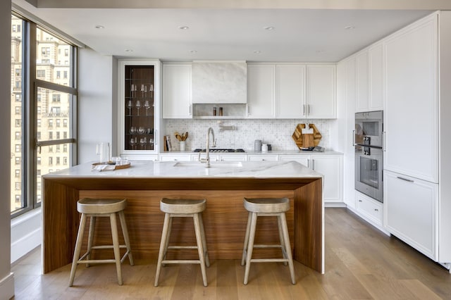 kitchen with a sink, plenty of natural light, decorative backsplash, and white cabinetry
