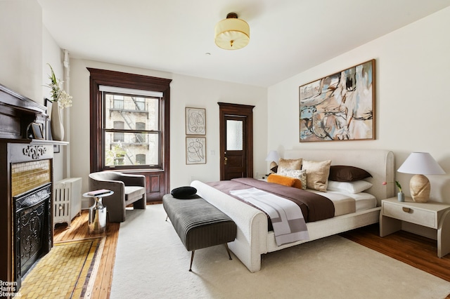 221 W 113th St, New York City, NY 10026 - bedroom featuring a tiled fireplace, wood finished floors, and radiator