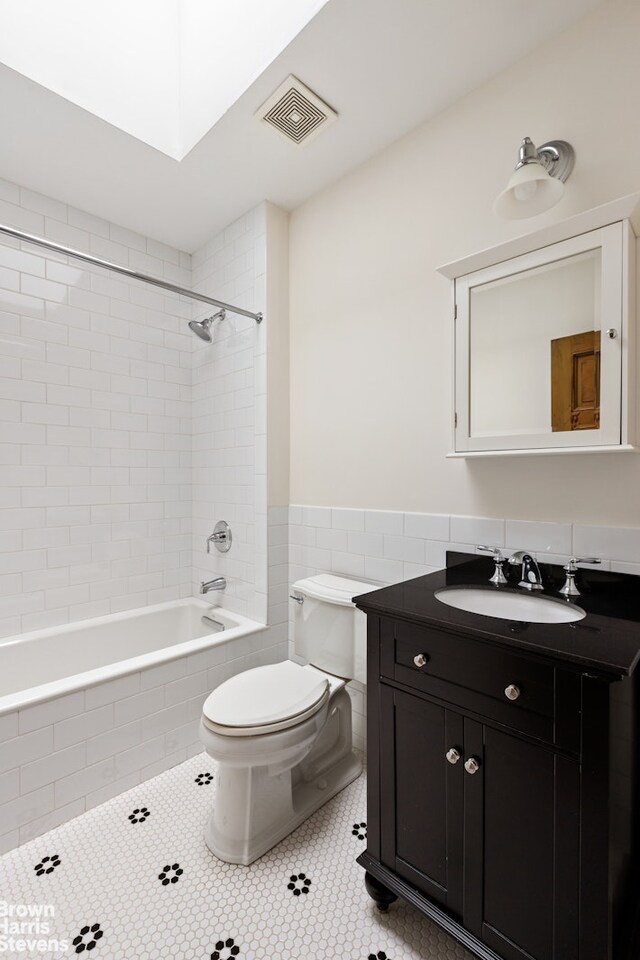221 W 113th St, New York City, NY 10026 - bathroom with toilet, tile patterned floors, tiled shower / bath, tile walls, and vanity