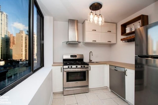 300 E 90th St Unit 9B, New York City, NY 10128 - kitchen featuring appliances with stainless steel finishes, wall chimney range hood, a sink, light tile patterned floors, and white cabinets