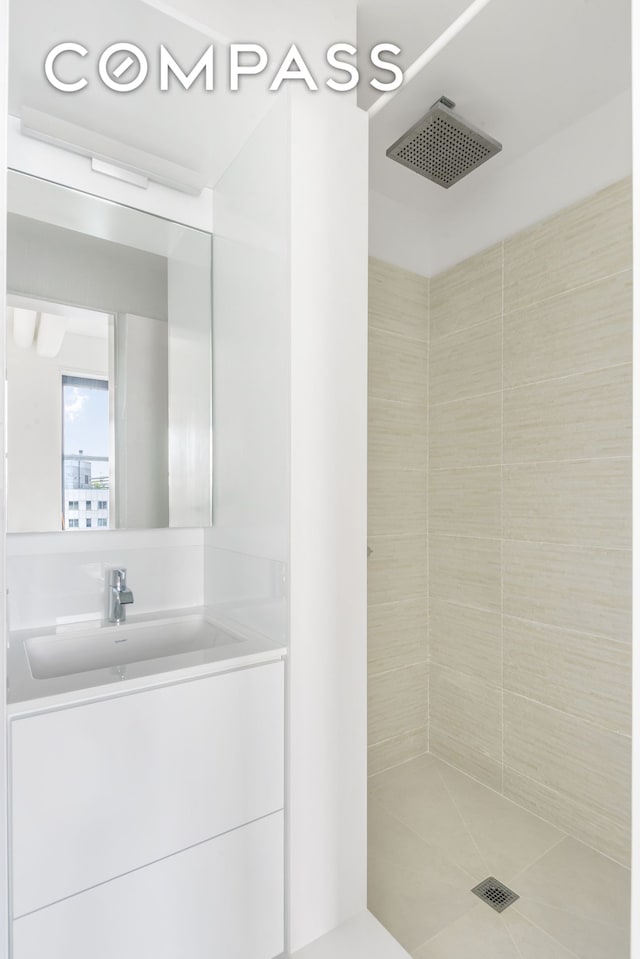 full bathroom with tiled shower, vanity, and tile patterned flooring