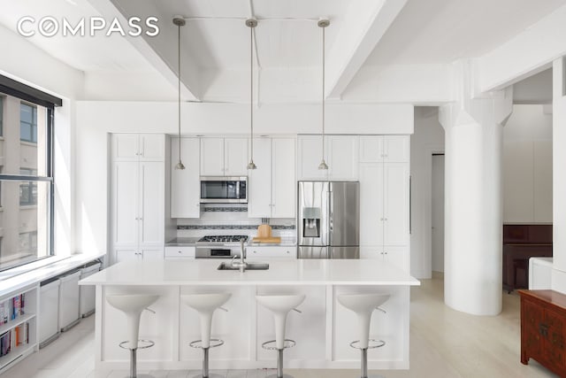 kitchen with appliances with stainless steel finishes, a sink, light countertops, and an island with sink