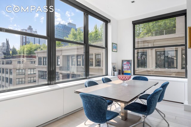dining area featuring a view of city, healthy amount of natural light, and light wood-style flooring