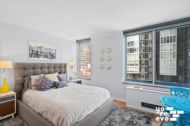 bedroom featuring wood finished floors, crown molding, and baseboards