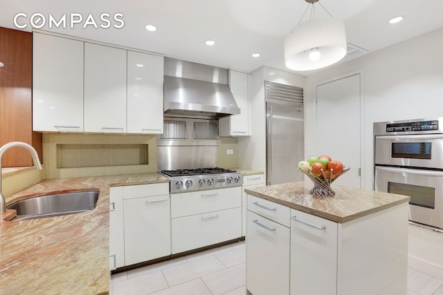 344 W 23rd St Unit 1E, New York City, NY 10011 - kitchen featuring wall chimney exhaust hood, a sink, appliances with stainless steel finishes, white cabinets, and recessed lighting