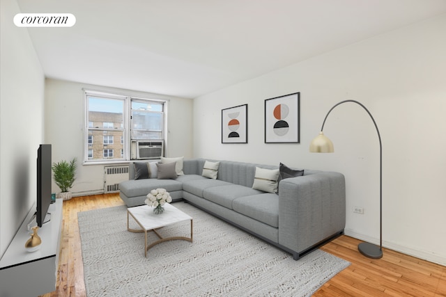 living area with radiator heating unit, light wood-style floors, and cooling unit