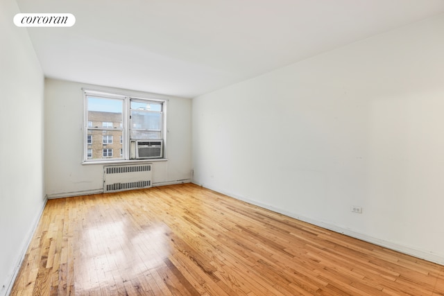 unfurnished room with radiator, hardwood / wood-style flooring, cooling unit, and baseboards