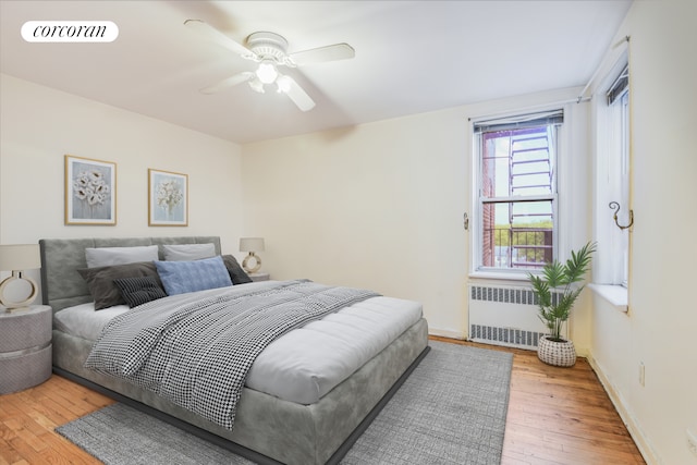 bedroom with radiator, wood-type flooring, a ceiling fan, and baseboards